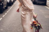 an ivory silk sheath wedding dress with a high neckline, puff sleeves on buttons and white embellished shoes