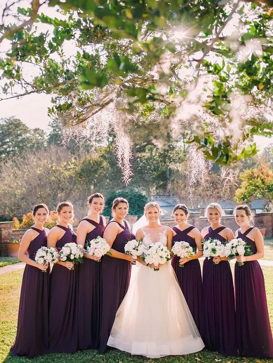 Elegant purple maxi bridesmaid dresses with criss cross necklines and pleated skirts are a gorgeous idea for the fall