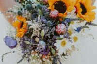 a beautiful and colorful wedding bouquet of pink and purple blooms,chamomiles, thistles, sunflowers and baby’s breath is amazing
