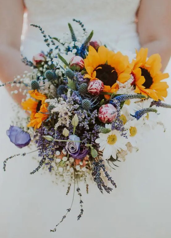 a beautiful and colorful wedding bouquet of pink and purple blooms,chamomiles, thistles, sunflowers and baby's breath is amazing