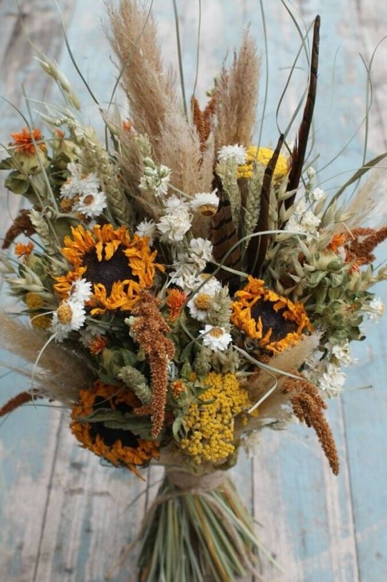 a beautiful dried flower wedding bouquet with pampas grass, sunflowers, astilbe, daisies, greenery for a fall or summer boho bride