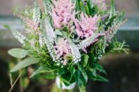 a beautiful small wedding bouquet of pink and white astilbe and greenery with a white ribbon wrap is amazing