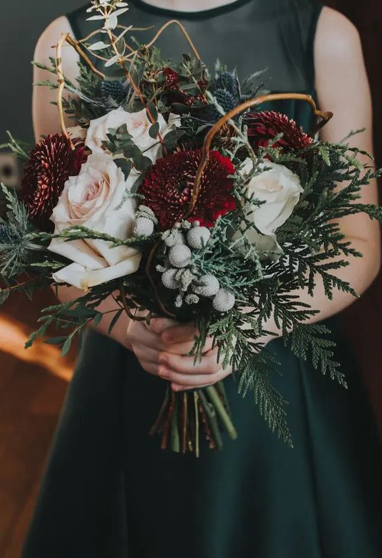 a beautiful winter wedding bouquet of white, blush and burgundy blooms, greenery, twigs, thistles and berries is a moody and chic idea to try