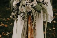a beautiful woodland wedding bouquet of various types of greenery, white blooms and grasses and colored ribbons