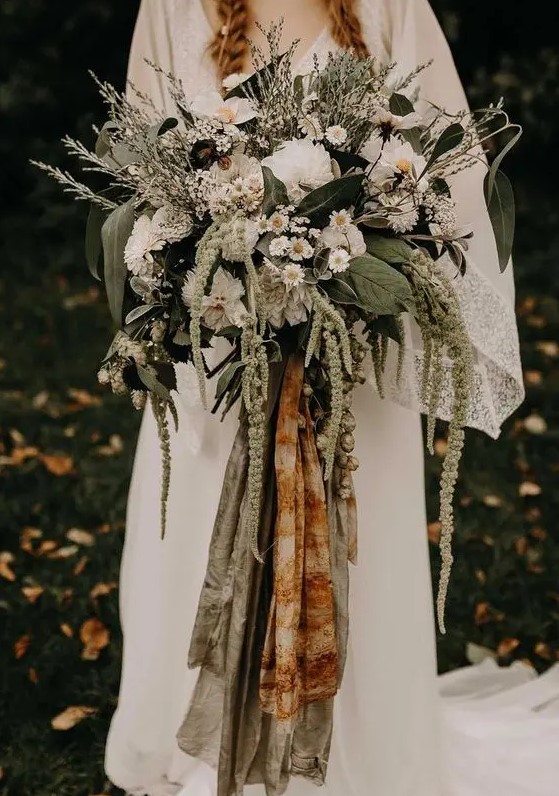 a beautiful woodland wedding bouquet of various types of greenery, white blooms and grasses and colored ribbons