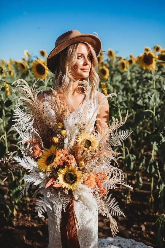 a boho fall wedding bouquet of sunflowers, dried and spray painted leaves, billy balls, colorful ribbons is a cool idea to rock