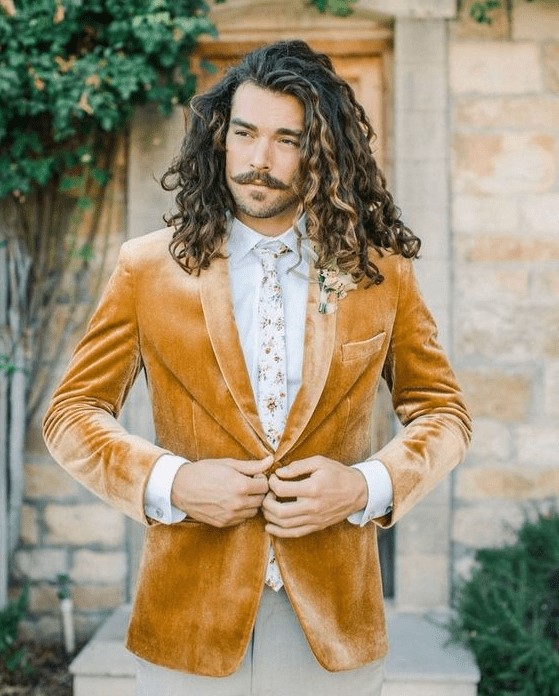 a boho groom's look with a yellow velvet blazer, a white shirt, a floral tie and grey pants plus a floral boutonniere