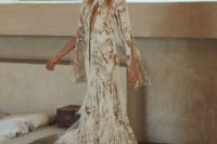 a boho nude lace A-line wedding dress with a deep plunging neckline, bell sleeves and long fringe