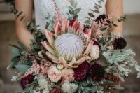 a boho summer wedding bouquet of greenery, blush and purple blooms, a giant king protea and eucalyptus
