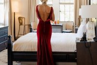 a bride wearing a jaw-dropping burgundy velvet mermaid wedding dress with a cutout back and a pearl necklace to accent it