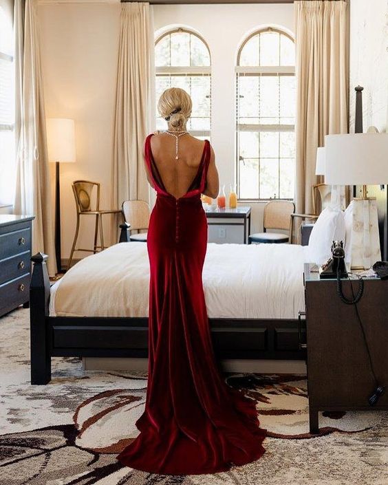 a bride wearing a jaw-dropping burgundy velvet mermaid wedding dress with a cutout back and a pearl necklace to accent it