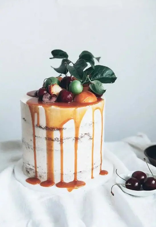 a caramel drizzle semi naked wedding cake topped with citrus, cherries and fresh leaves for a summer wedding