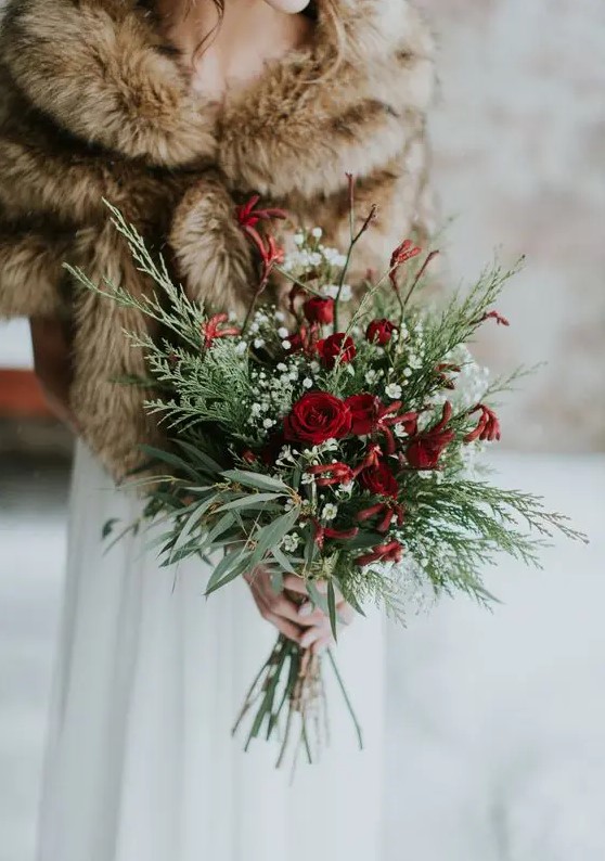 a chic and simple winter wedding bouquet of evergreens and greenery, baby's breath and red roses