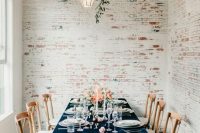 a chic wedding tablescape with a navy velvet tablecloth, coral blooms, candles and neutral porcelain and cutlery is amazing