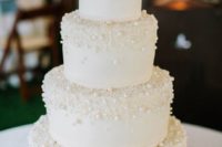 a chic white wedding cake covered with edible pearls is ultimate elegance that works for most of weddings