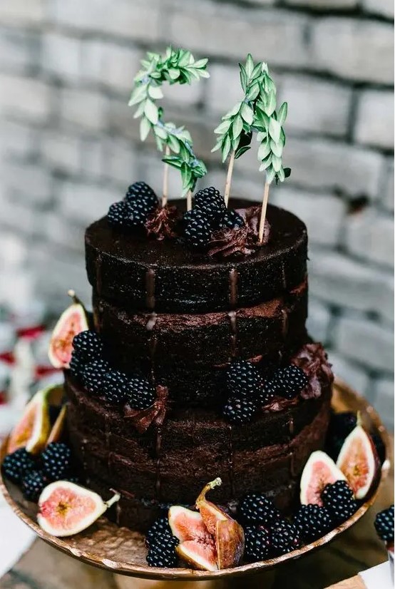 a chocolate naked wedding cake with blackberries, figs and greenery is a great choice for a fall wedding with a boho feel