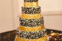 a chocolate wedding cake with glitter ribbons and dark blooms and a gold glitter calligraphy topper is very glam and chic