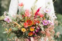 a colorful and textural fall wedding bouquet of pink and hot pink blooms, orange ones and lots of blooming branches