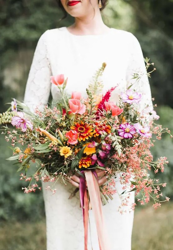 a colorful and textural fall wedding bouquet of pink and hot pink blooms, orange ones and lots of blooming branches