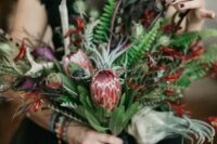 a colorful and textural wedding bouquet with proteas, herbs and greenery plus balck ribbons
