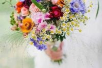 a colorful wildflower wedding bouquet in purple, yellow, pink, fuchsia and with greenery and herbs