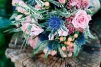 a cute bouquet with blue thistles, soft pink garden roses and some greenery for a sweet summer look
