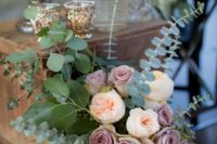 a dimensional wedding centerpiece of eucalyptus, blusha dn mauve blooms and a clear vase