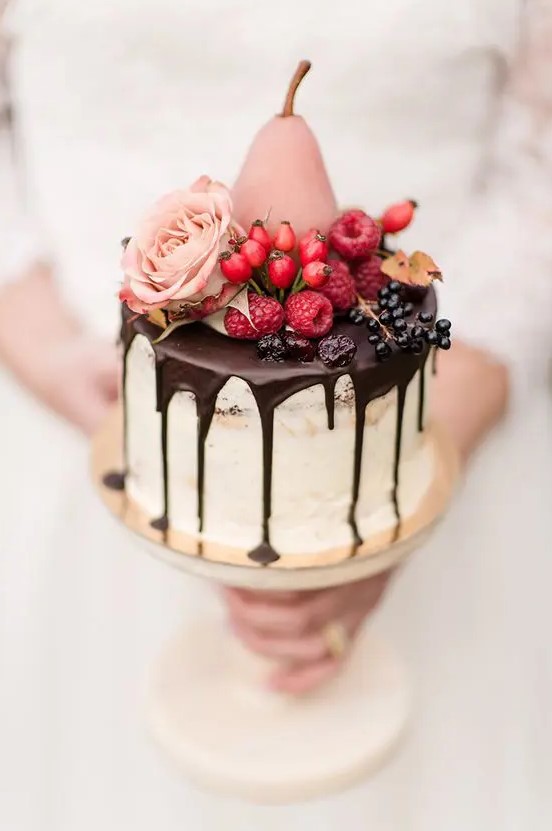 a dreamy fall wedding cake with chocolate drip, fresh berries, a pink rose and a pink candied pear is amazing and mouth watering