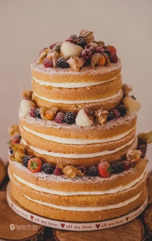 a fab and delicious naked wedding cake with fresh berries and fruit on top is a gorgeous idea for a refined summer wedding