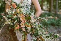 a fab oversized wedding bouquet of peachy and rust-colored blooms, greenery, white fillers and various foliage for the fall