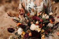 a fall wedding bouquet with marigold, burgundy and pink blooms, feathers, dried touches and berries