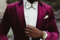 a glam groom in a plum-colored velvet tuxedo, a white shirt and an embellished white bow tie