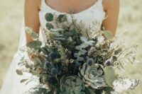a greenery wedding bouquet with eucalyptus, blue thistles and succulents looks very romantic