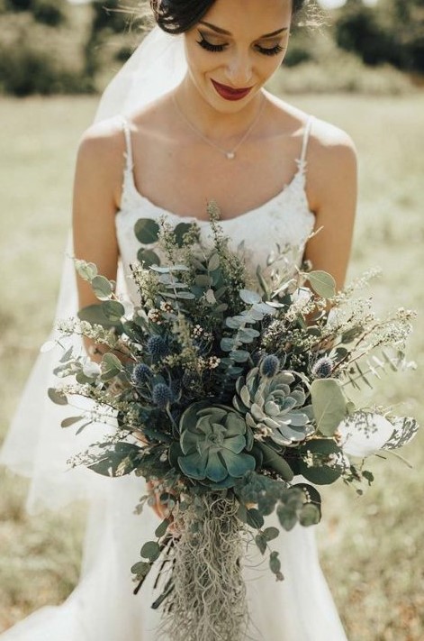a greenery wedding bouquet with eucalyptus, blue thistles and succulents looks very romantic