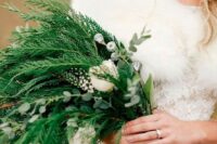 a greenery wedding bouquet with some berries and white blooms with a catchy relaxed shape