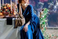 a jaw-dropping blue velvet wedding dress with a cowl neckline and bell sleeves and a train is a beautiful idea for a wedding