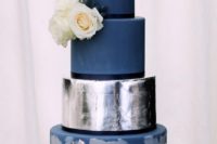 a large navy and silver foil wedding cake with various tiers and fresh blooms