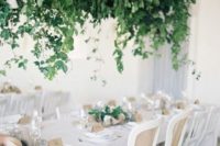 a lush cascading greenery wedding decoration with some white blooms