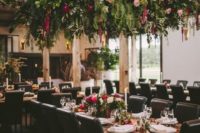 a lush greenery and floral overhead wedding decoration and matching centerpieces