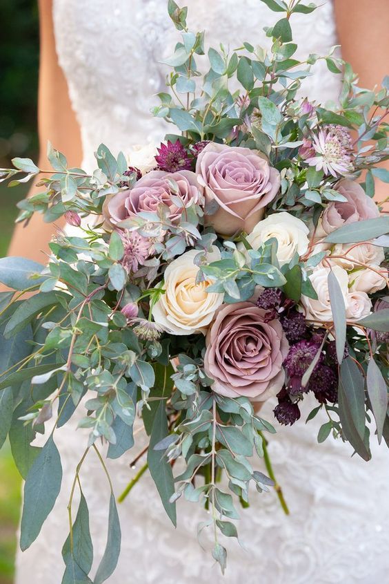 a lush textural wedding bouquet with greenery, mauve, purple and ivory blooms