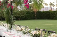 a lush tropical overhead wedding decoration with pink and blush blooms and tropical leaves