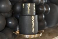 a matte black wedding cake decorated with gold patterns looks very chic and refined