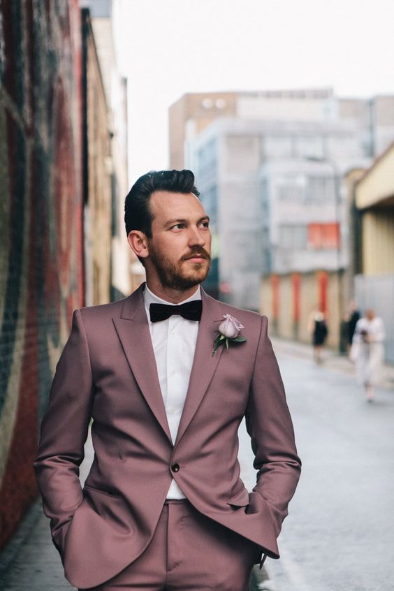 a mauve groom's suit with a white shirt and a burgundy velvet bow tie for a unique look
