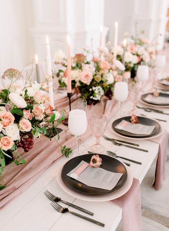 a mauve table runner and napkins plus blush and white blooms plus candle to make up a chic and refined look