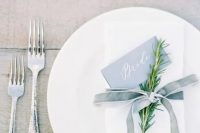 a minimalist table setting with a white napkin and a dusty blue velvet ribbon