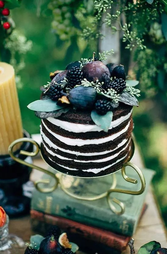 a naked chocolate wedding cake topped with fresh fruit and berries, with greenery is a fantastic and yummy looking idea for a fall wedding