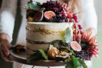 a naked wedding cake with a gold touch, with lots of fresh fruit and berries and dark blooms on top is a gorgeous idea for a fall wedding