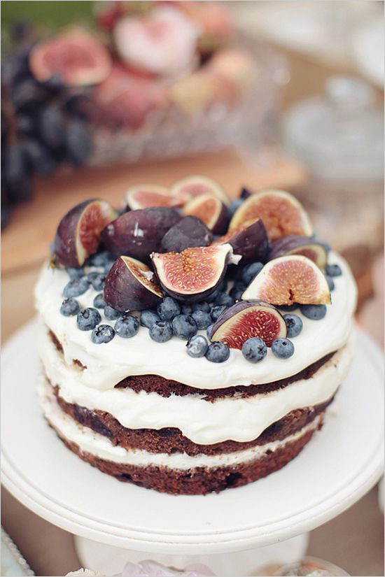 a naked wedding cake with fresh figs and blueberries on top is a cool idea for a summer or fall wedding