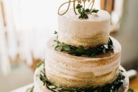 a naked wedding cake with gold touches, greenery and a gold glitter calligraphy topper is a lovely idea for a NYE wedding