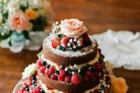 a naked wedding cake with lots of berries and fresh blooms, with greenery is a lovely solution for a spring or summer boho wedding cake